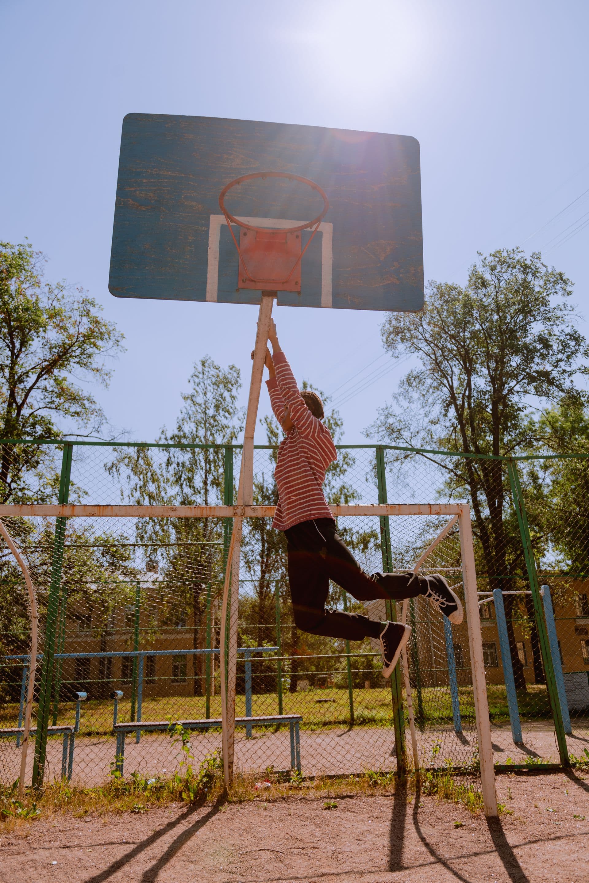 A teenager jumping for a basketball hoop outdoors